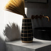 Vase with a broom on a concrete surface next to a black sink and faucet.
