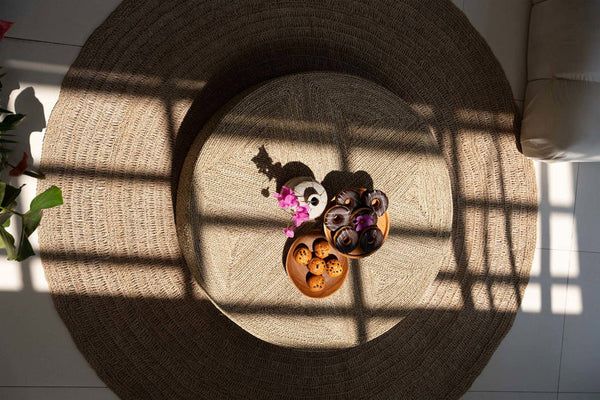Decorative items on a round woven mat with sunlight casting shadows