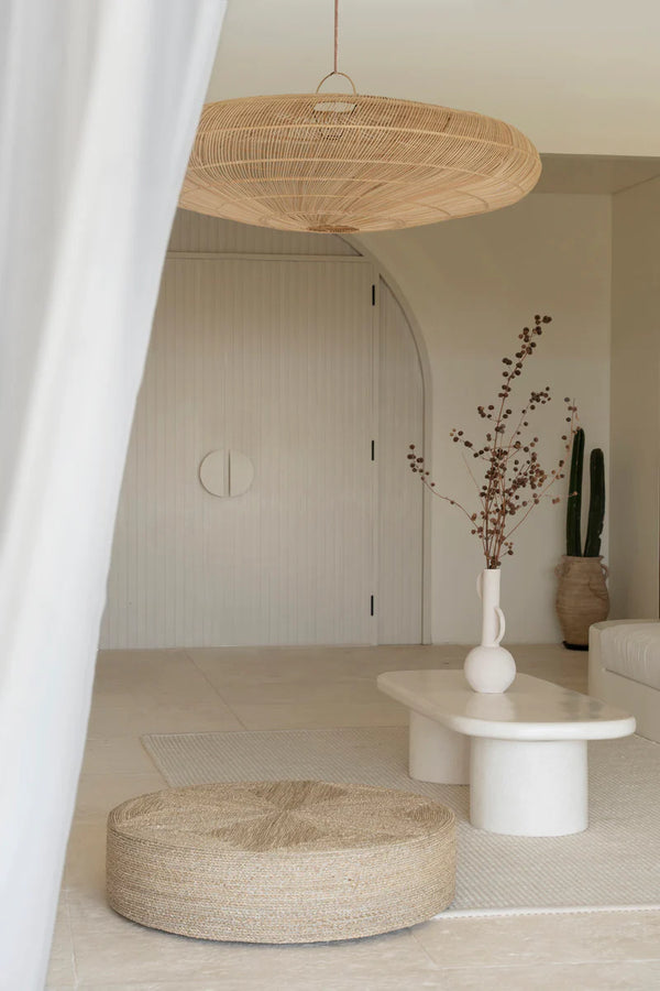 Modern interior with a woven ottoman, white table, and decorative elements.