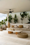 Modern outdoor living space with a white sofa, coffee table, and decorative plants.