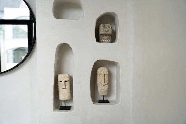 Wooden sculptures of faces embedded in a white wall