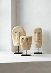 Three stone face sculptures on stands against a white background