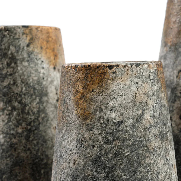 Close-up of textured stone or concrete cylindrical objects with a neutral background