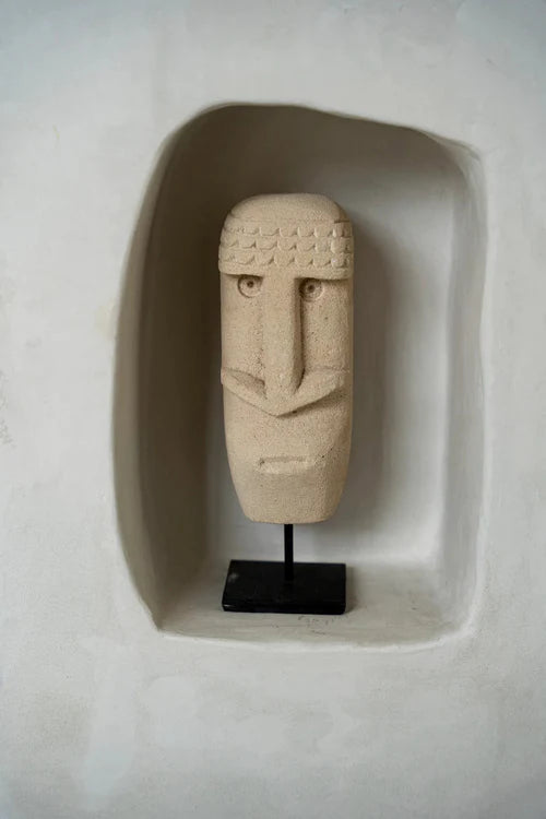 Stone face sculpture on a stand inside a recessed alcove.