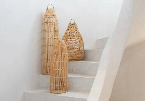 Three woven rattan lanterns on a staircase with a white wall background