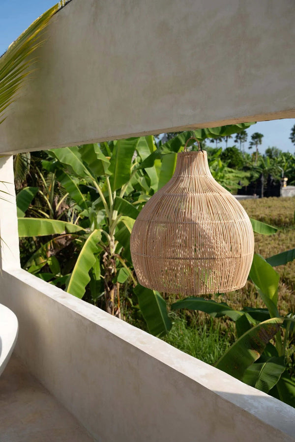 Woven basket hanging outdoors with greenery and a clear sky