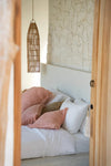 Bed with pink and white pillows against a stone wall
