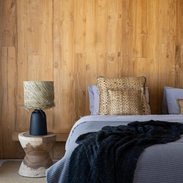 Bedroom with wooden wall, bed with pillows, and lamp on a side table.