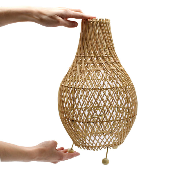 Woven rattan lampshade held by a hand on a white background