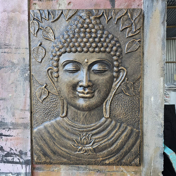 Bronze relief of a Buddha face on a textured wall