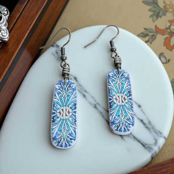 Decorative earrings with blue and white pattern on a marble surface