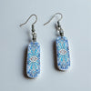 Pair of blue and white patterned earrings on a light gray background