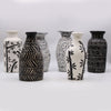 Set of six ceramic vases with black and white patterns on a light gray background