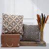 Decorative pillows and a wooden box on a white surface with a white wall background