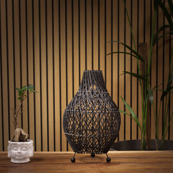 Woven rattan vase on a wooden surface with a striped wall background