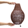 Woven brown lampshade held by a hand on a white background