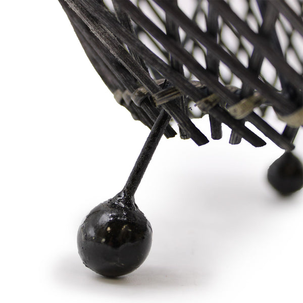 Close-up of a black metal basket with spherical ends on a white background