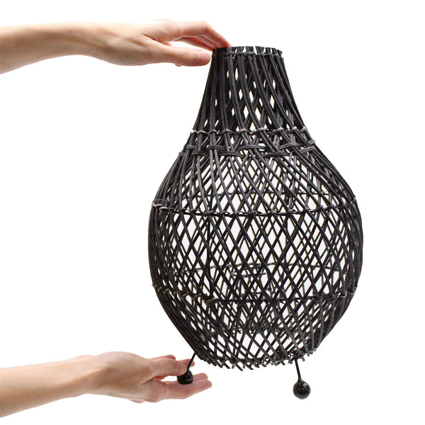 Black woven lampshade held by a hand on a white background