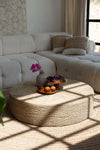 Living room with a white sectional sofa and a round woven coffee table.