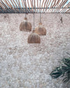 Three woven pendant lights hanging against a textured stone wall.