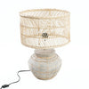 Table lamp with rattan shade and textured base on a white background