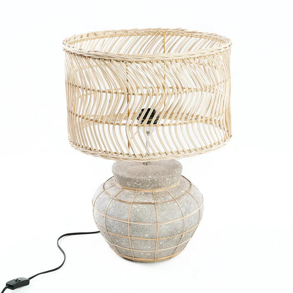 Table lamp with rattan shade and textured base on a white background