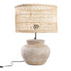 Table lamp with wicker basket shade and textured base on a white background