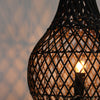Woven black lampshade with a glowing light bulb against a blurred background