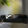 Black leather bench with cowhide pattern against a gray wall