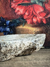 Decorative stone bowl with a floral painting in the background