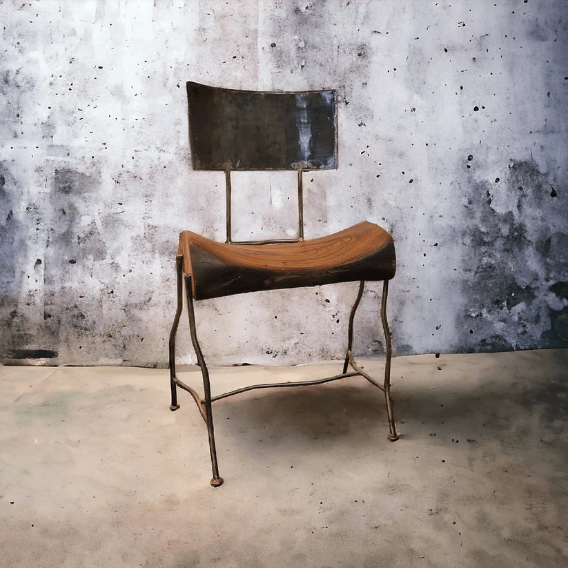 Chair with wooden seat and metal frame against a textured wall.