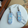 Decorative earrings with blue and white pattern on a marble surface